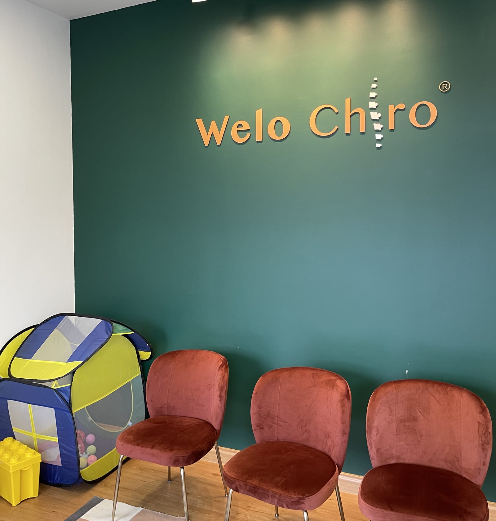 The waiting area at Welo Chiro Taman Wahyu, with the Welo Chiro sign above the chairs and a play tent for children